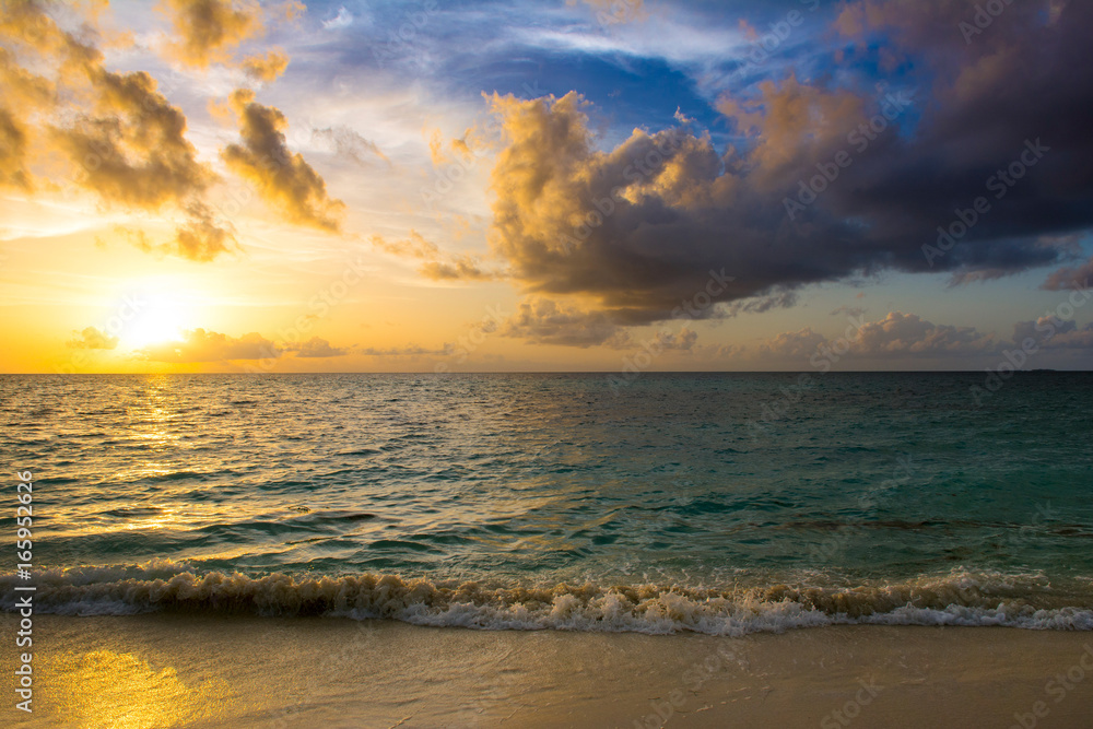 Landscape of beautiful sunset in Maldives island sandy beach with colorful sky over wavy sea Landscape of beautiful sunset in Maldives island sandy beach with colorful sky over wavy sea
