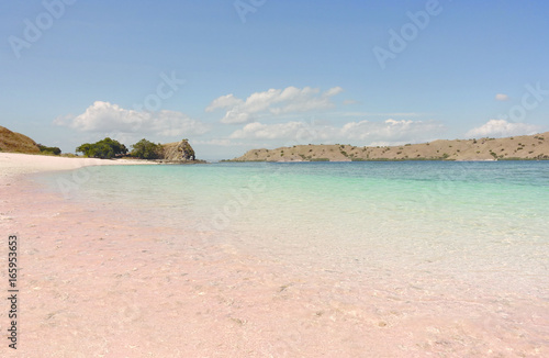Tropical pink sand beach in Flores caused by peaces of broken red pink colored coral in the ocean during the day.