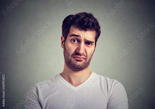frowning young man thinking expressing doubts and concerns
