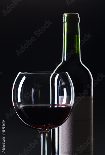 Bottle and glass of red wine .