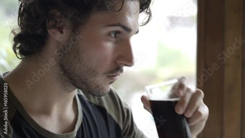 Handsome teenager drinking cola sitting at the table in the pub