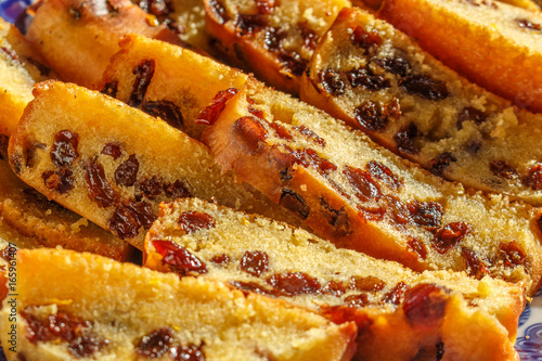 Freshly baked and sliced sponge fruit cake with raisins on plate