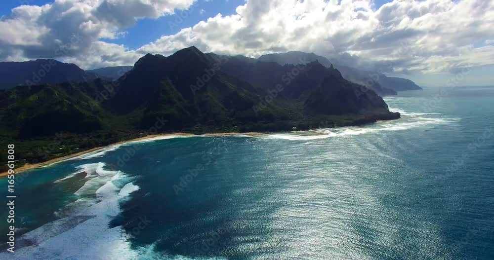 High-Altitude View of Coastal Beach with Whitewater Breakers on Shore and Small Peninsula Mountains Jutting into the Sea Under a Cloudy Sky - Aerial Footage from Kaua, Hawaii