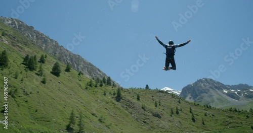 A man flying through the air from a water jump lands in a lake with a splash