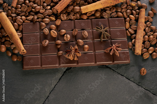 Top view of arabica coffee beans cinnamon star anise dark chocolate on black stone background with copy space