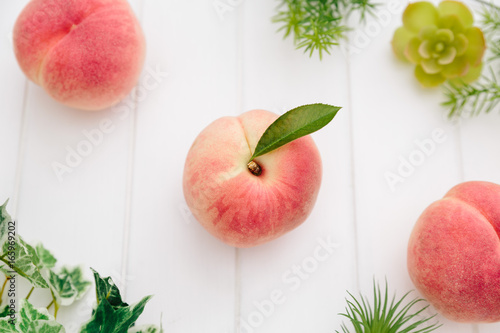 Fresh Japan White Peaches and Green Leaves on Wooden White Background  © SHIN