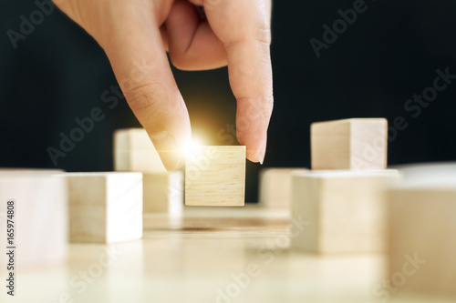 Hand of male pick up on one wooden block from many, Business ideas for choosing something that looks distinctive concept photo