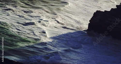 Slow motion, waves crash on rocky cliffs