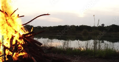 Pan left, campfire near lake at sunset