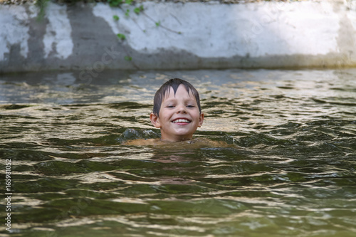 Fototapeta Naklejka Na Ścianę i Meble -  Smiling boy swimming in lake