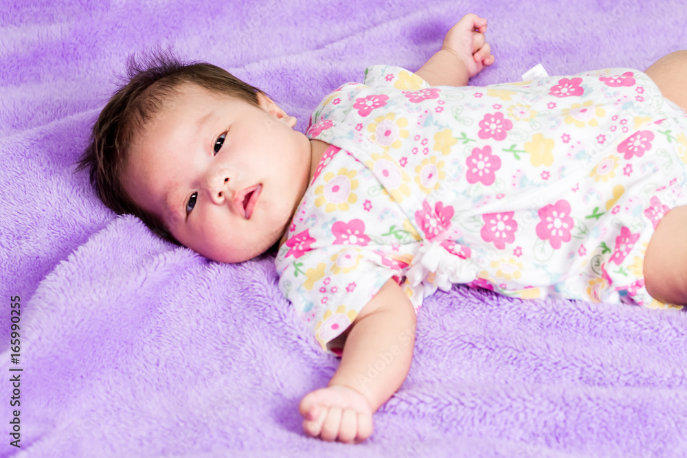 Portrait of a little adorable infant baby girl lying on the back on the bed Portrait of a little adorable infant baby girl lying on the back on the bed