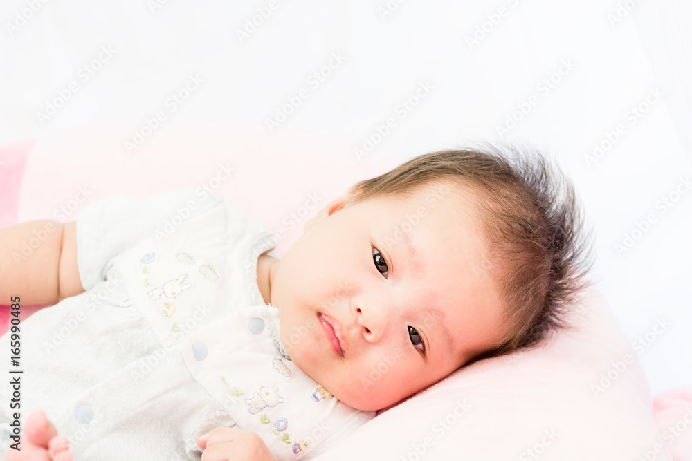 Portrait of a little adorable infant baby girl lying on back on the pillow Portrait of a little adorable infant baby girl lying on back on the pillow