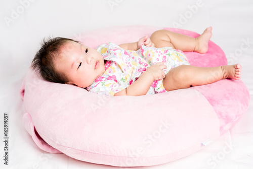 Portrait of a little adorable infant baby girl lying on back on the pillow