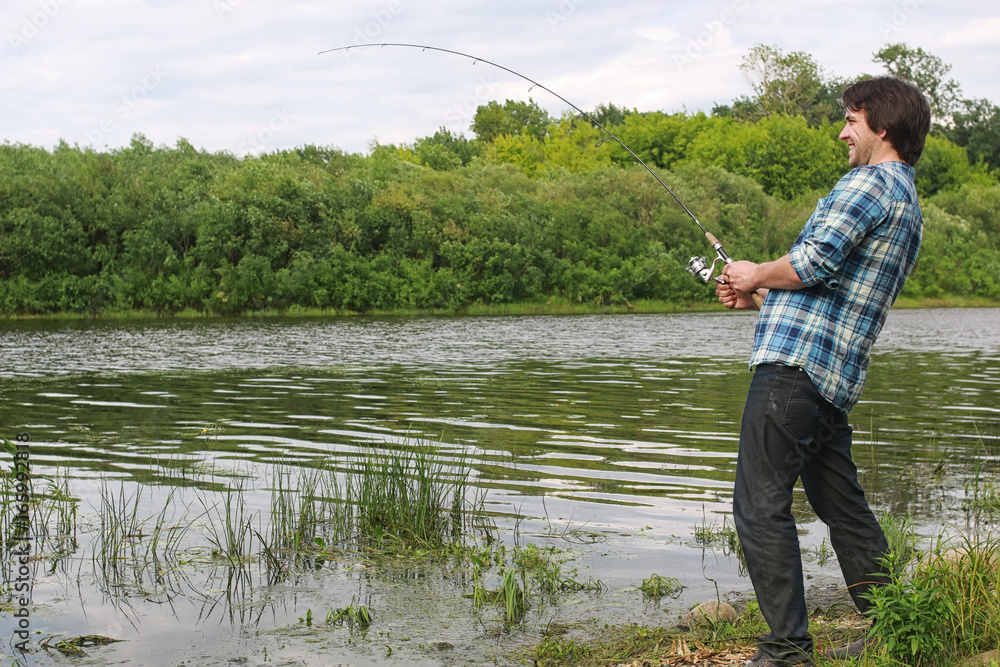 A man with a beard is fishing in the river A man with a beard is fishing in the river