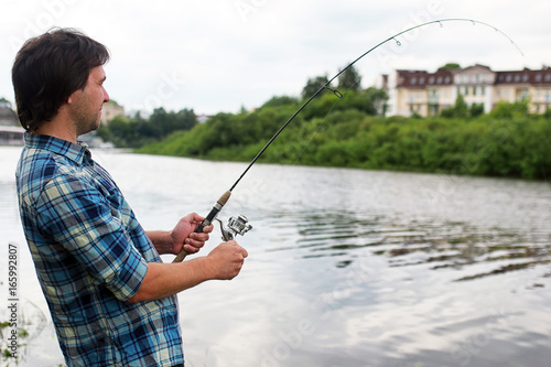 A man with a beard is fishing in the river