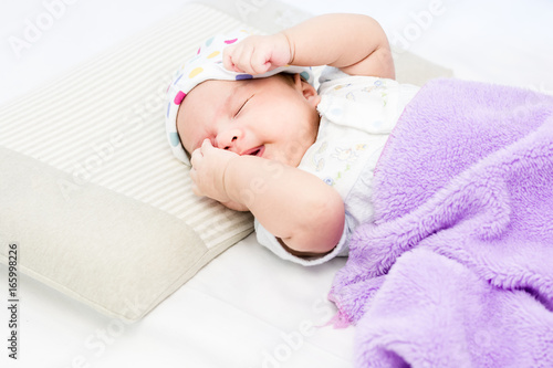 Portrait of sleeping baby  lying on a bed with hat