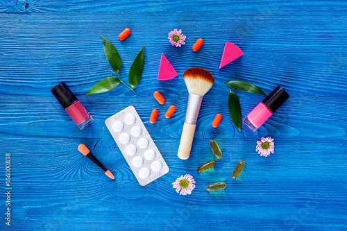 Contents of wonam's beauty bag. Cosmetics and pills on blue table background top view copyspace photo