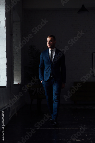 Young attractive and confident businessman in blue suit and black tie. © photominus21
