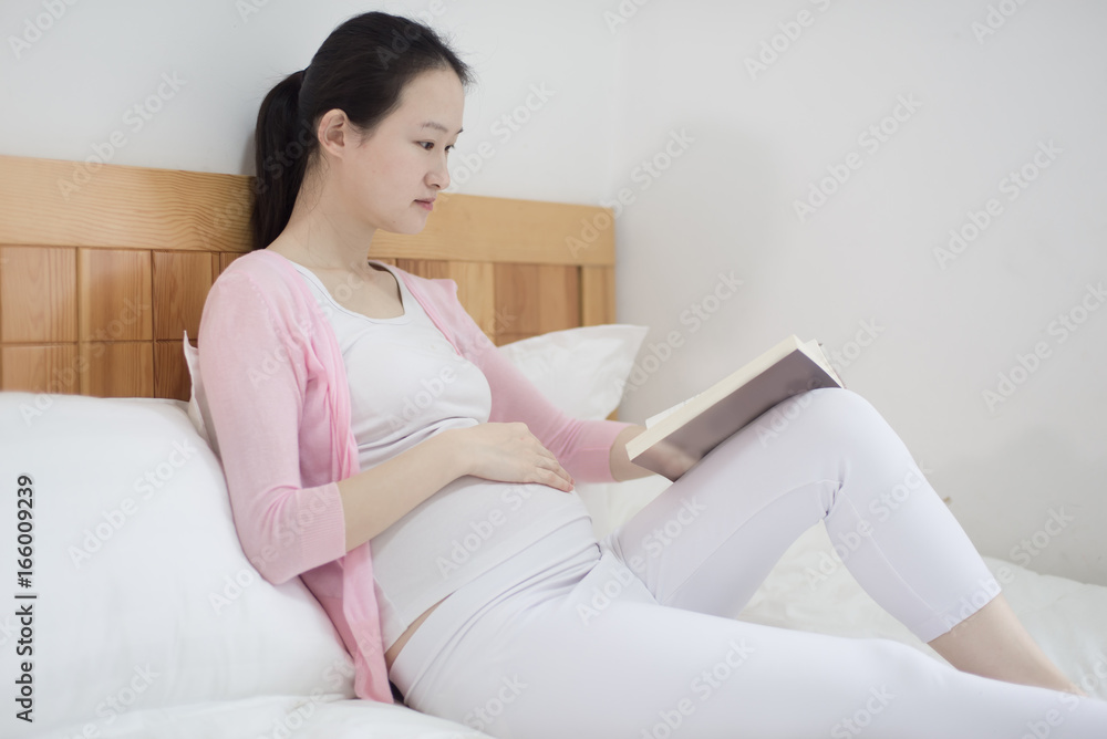 Pregnant Woman Drinking Hot Drink And Reading Book At Home Pregnant Woman Drinking Hot Drink And Reading Book At Home