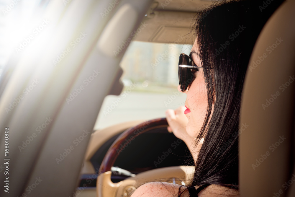 Portrait of a beautiful brunette with glasses that sits in a luxury car. Portrait of a beautiful brunette with glasses that sits in a luxury car.