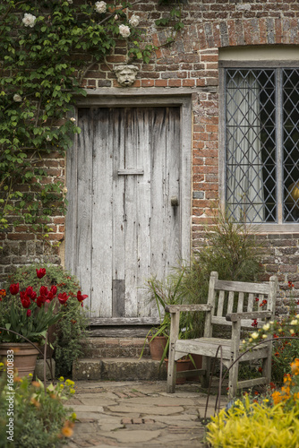 Quintessential old English country garden image of wooden chair next to vintage back door
