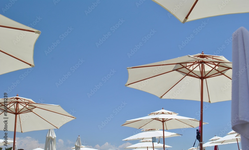 Beach umbrellas against the sky/ Open umbrellas on the beach on blue sky background