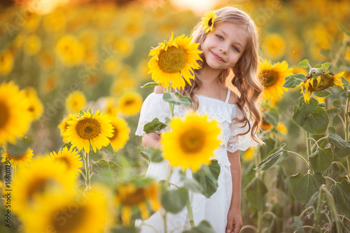 Beautiful child girl in yellow garden of sunflowers