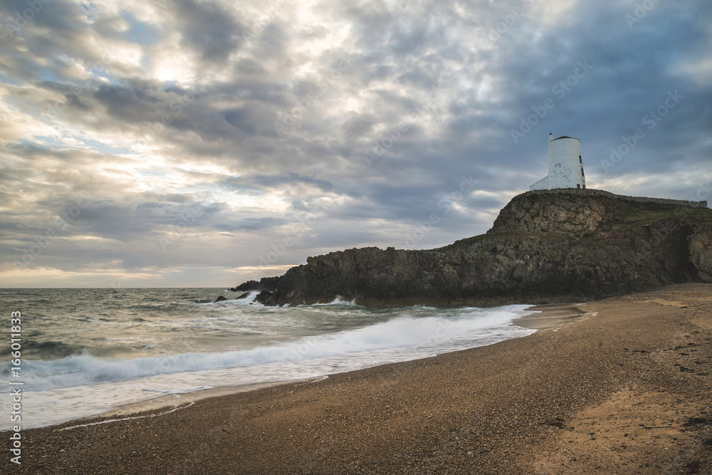Stunning Twr Mawr lighthouse landscape from beach with dramatic sky and cloud formations