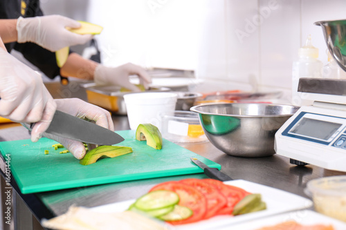 Female chef cutting avocado in kitchen