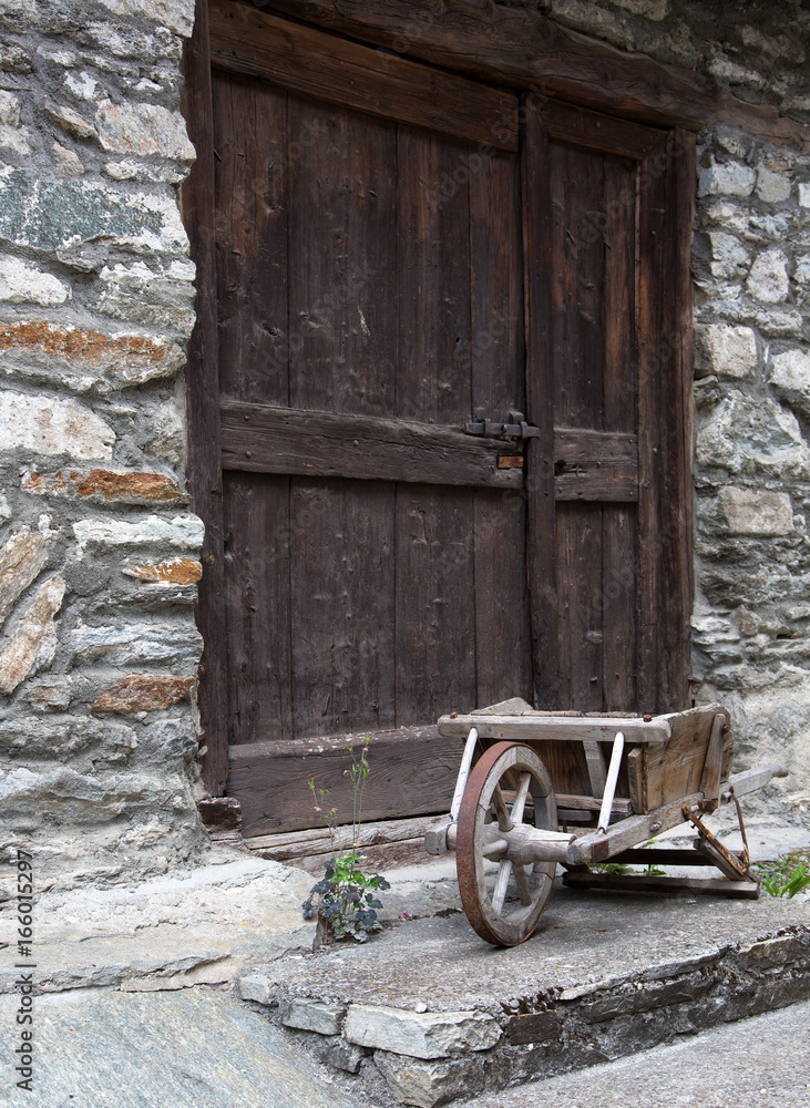 Ancienne brouette en bois devant une porte