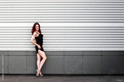 Sports brunette with a beautiful body in black dress on light snow background. Copy space.