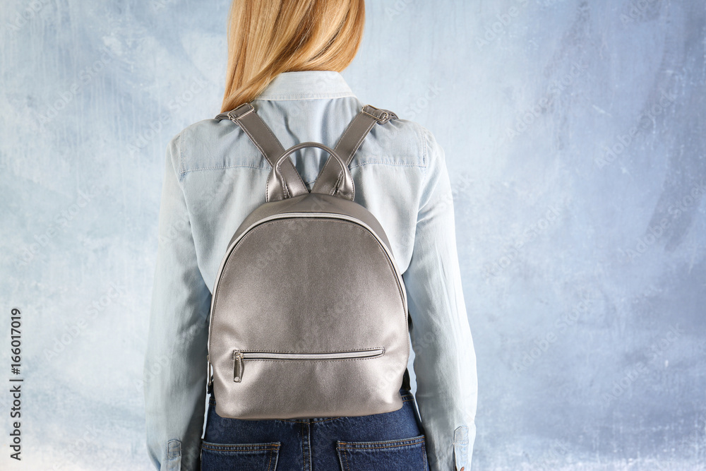 Fotografie Young woman with leather backpack on light background