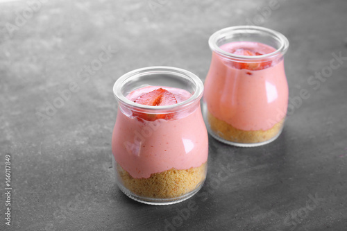 Homemade strawberry dessert with yogurt in glass jars on grey background