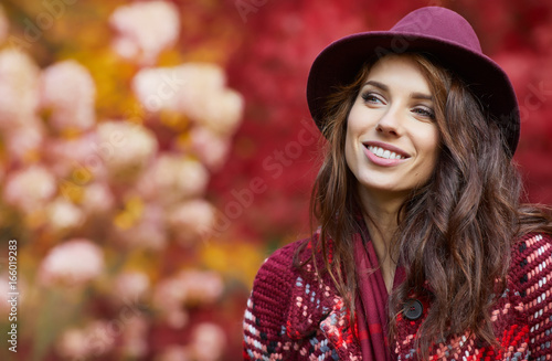 Woman in coat with hat and scarf in autumn park