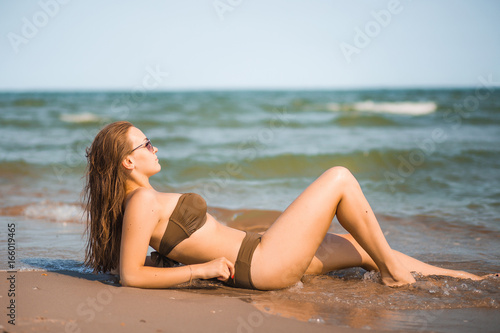 Sexy tanned girl in a bathing suit lies on the seashore