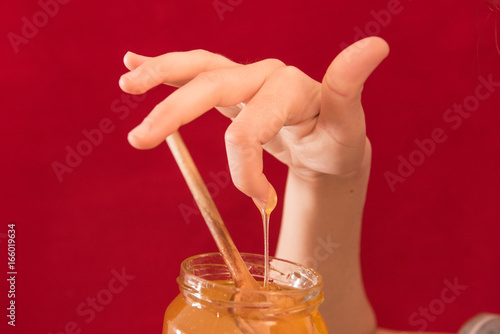 Girl eating honey with wooden spoon and licking