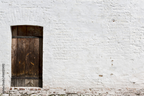 Heavy closed door on a stone wall of a medieval fortress, made of riveted wood