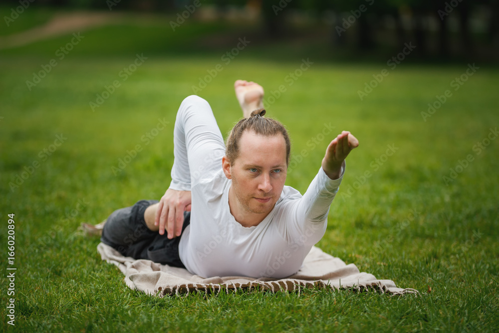 Fototapeta premium Hipster man - yoga instructor performs flexibility exercises in park