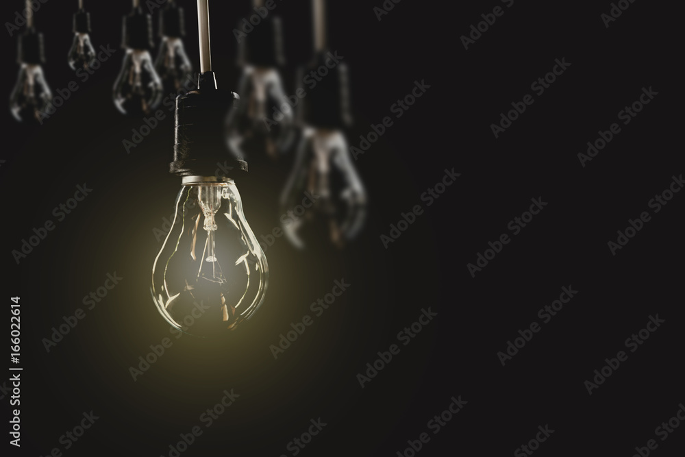 Hanging light bulbs with glowing one on dark background. Idea and creativity concept with light bulbs.