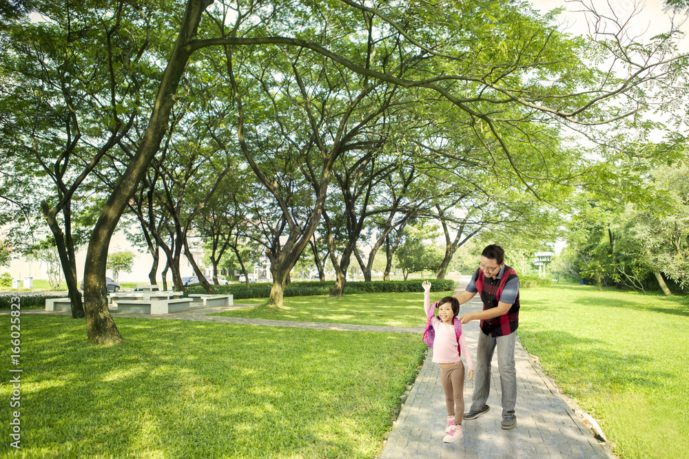 Fototapeta premium Young father wearing a backpack to her daughter