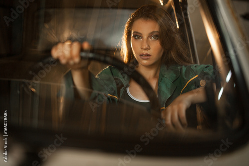 Portrait of woman driver behind steering wheel of car. View through windscreen.