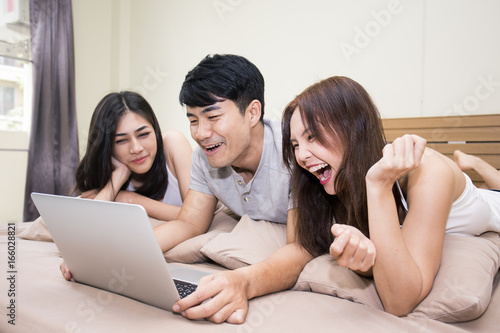 Asian man and woman using computer on bed, Young people portrait in bedroom, vintage color tone.