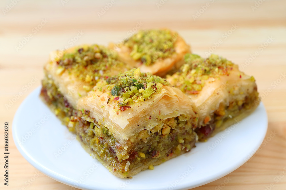 Closed up of Baklava with Pistachio Nuts Served on White Plate, Blurred Background 