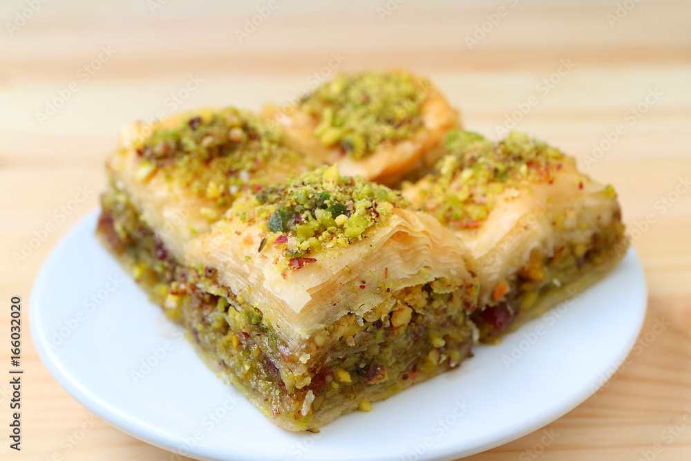 Closed up of Baklava with Pistachio Nuts Served on White Plate, Blurred Background Closed up of Baklava with Pistachio Nuts Served on White Plate, Blurred Background