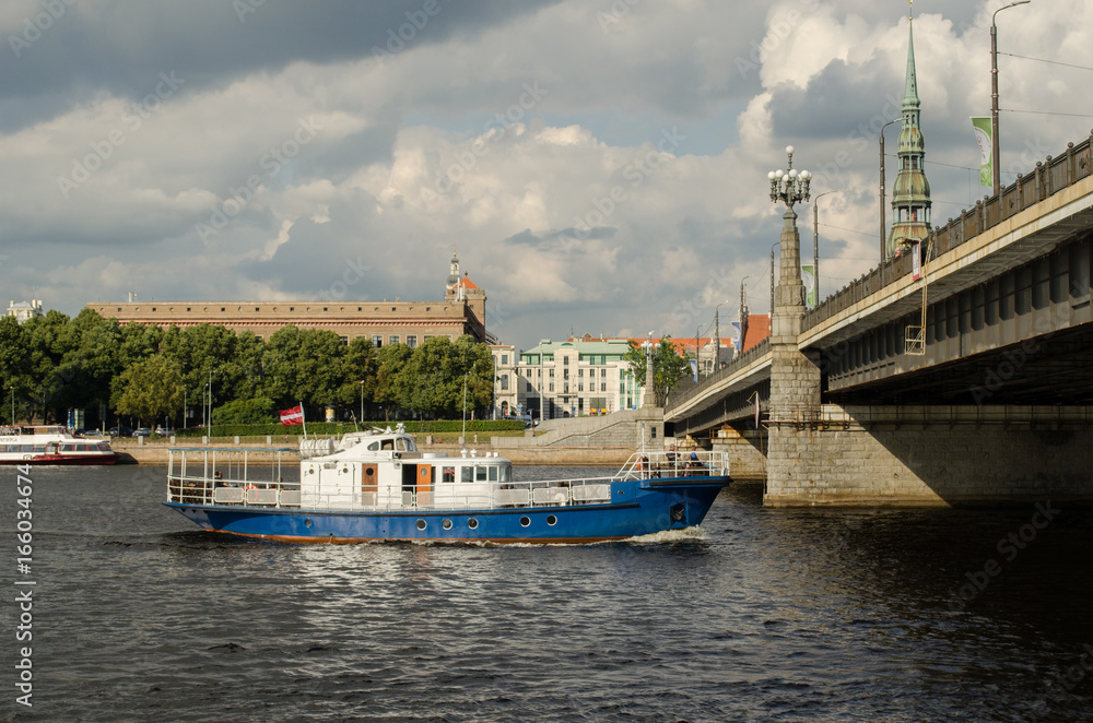 Boat Ferry going under the Stone Bridge on Daugava River in Riga