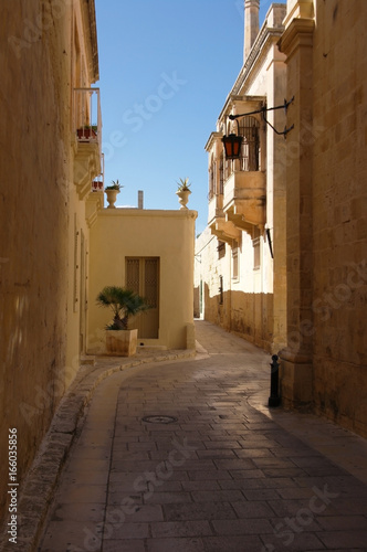 Fototapeta Naklejka Na Ścianę i Meble -  Shadowed narrow historical street of Mdina, old town, in Malta on a sunny day.