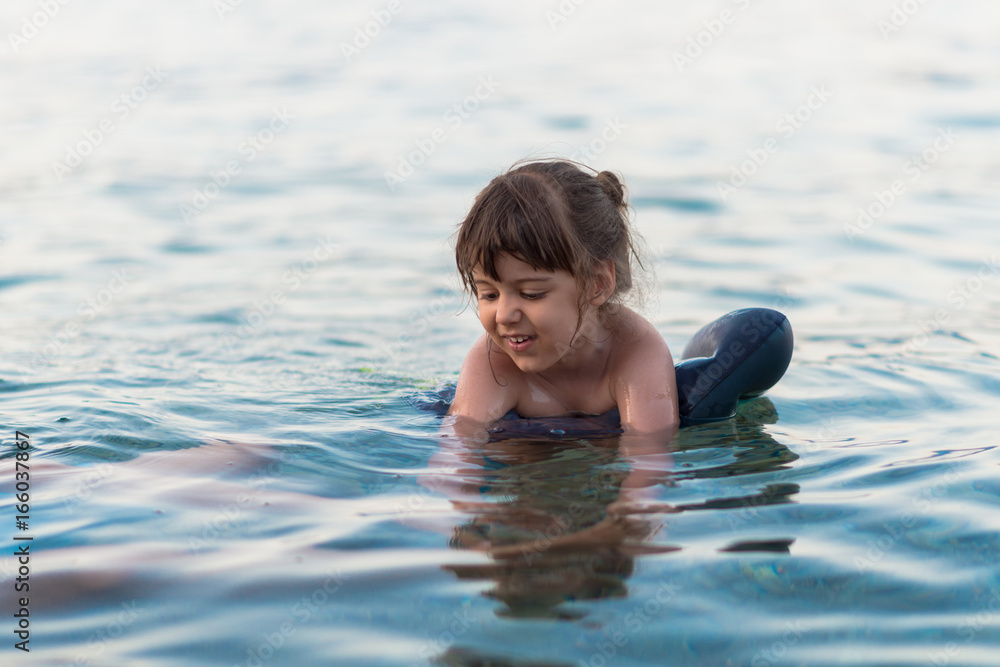 Little child learning to swim at the sea 