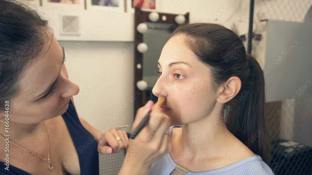 Young beautiful woman applying make-up by make-up artist in slow motion Young beautiful woman applying make-up by make-up artist in slow motion