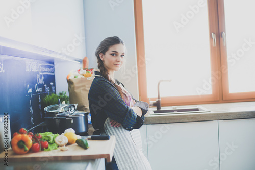 Young woman sitting on table in the kitchen.