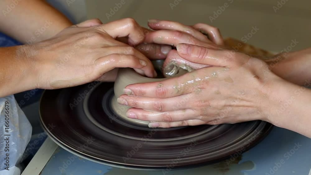 Hands of two people create pot, potter's wheel. Teaching pottery Hands of two people create pot, potter's wheel. Teaching pottery